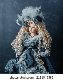 Neverovatna realistična vintage igračka sa plavim očima. Lutka obučena u plavu haljinu i ima plavu kosu. Selektivni fokus. Porcelan.