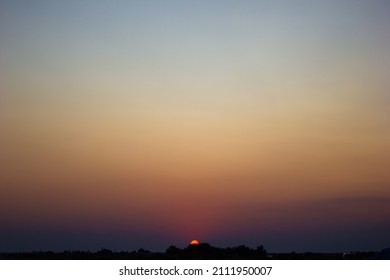 Cielo despejado al atardecer con horizonte naranja-violeta y atmósfera azul. Gradiente suave del cielo del amanecer con silueta de árboles. Fondo del cielo del amanecer del día que comienza temprano en la mañana.