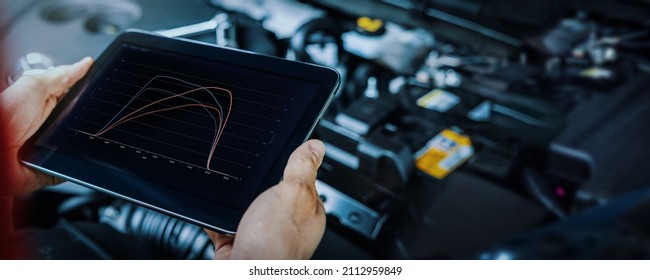 車のエンジン ECU の再マッピングと診断。デジタル タブレットを使用して、チップチューニング後に車両の性能をチェックする整備士