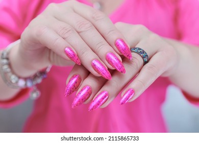 Manos femeninas con uñas largas y esmalte de uñas rosa neón.