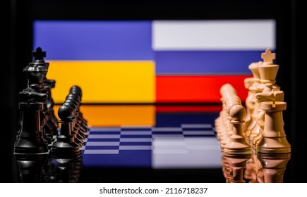 Konceptuelt billede af krig mellem Rusland og Ukraine ved hjælp af skakbrikker og nationale flag på en reflekterende baggrund
