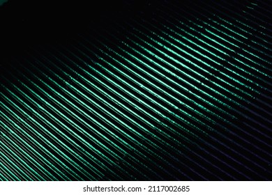 Corrugated texture. Neon light background. Grooved metal surface. Fluorescent green color gradient glow reflection on parallel lines pattern dark black abstract overlay.