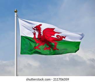De welsh vlag, een rode draak op een groene en witte achtergrond, wappert in de wind tegen een blauwe lucht.