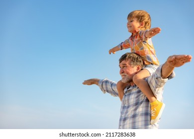 Pria senior dan anak di luar ruangan dengan latar belakang langit musim panas. Kakek dan anak laki-laki bersenang-senang bersama. Konsep liburan keluarga. Selamat Hari Ayah