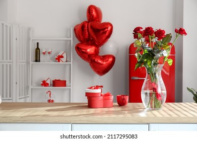 Vase mit Rosen, Tasse und Geschenkboxen auf der Theke im Zimmer, das für die Feier zum Valentinstag dekoriert ist