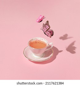 パステル ピンクの背景にヴィンテージのお茶の上を飛んでいる蝶。80 年代、90 年代のレトロな審美的なロマンチックな春または夏のコンセプト。最小限のファッション愛のアイデア。