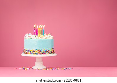 ピンクの背景に 5 つのキャンドルで青い誕生日ケーキ