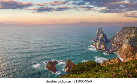 ポルトガル大西洋の大西洋岸にあるウルサビーチで、海岸線の絵のように美しい風景のパノラマの砂に岩と夕日の太陽の波と泡があります。緑の苔のある石。