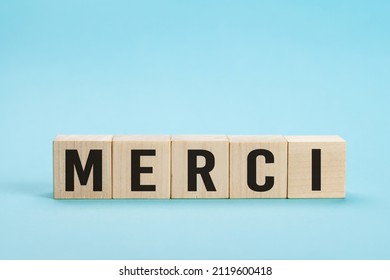 Merci - Thank you in French language. Merci Word on Letter Tiles on blue Background. Minimal aesthetics. Word merci thank you in french on wooden cubes