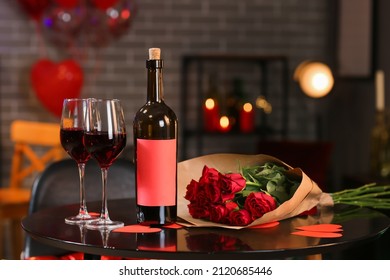 Flowers, bottle and glasses of wine on table in cafe. Valentine's Day celebration