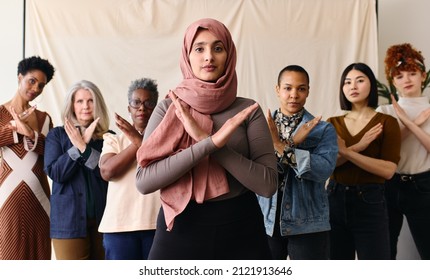 Frau aus dem Nahen Osten mit Hajib gestikuliert Break The Bias zur Unterstützung des Internationalen Frauentags mit Freundinnen