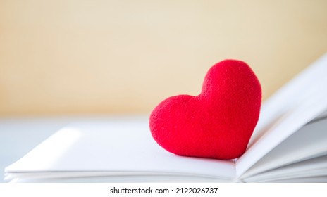 Red heart on book with space on blurred background, valentine day background idea, selective focus