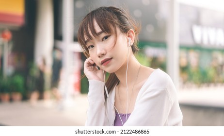 Người lớn trẻ tuổi nữ sinh viên đại học châu Á sử dụng tai nghe nhạc ngoài trời. Đại học nhân dân thành phố lối sống vào ngày khái niệm.