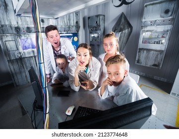 Man met vrouw en kinderen lossen puzzels op de computer op in een escape room, gestileerd als een laboratorium.