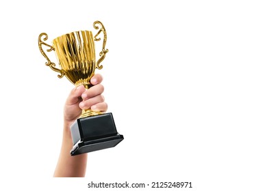 Copa de trofeo de oro brillante en la mano de un niño. Recompensa de niño campeón. Premio de concurso o concurso.