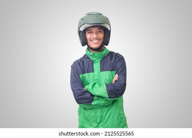 Portræt af asiatisk online taxachauffør iført grøn jakke og hjelm, stående med krydsede arme. Isoleret billede på hvid baggrund