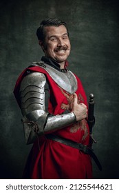 Polegar para cima. Retrato de um homem sorridente em imagem de um guerreiro medieval com o rosto ferido, usando equipamento isolado sobre fundo escuro. Comparação de eras, história e estilo renascentista. Emoções engraçadas de memes.