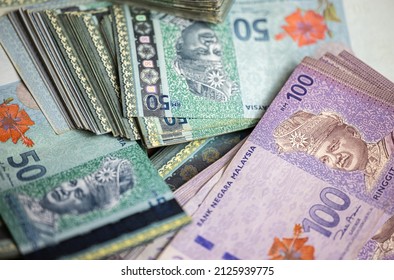 マレーシアリンギットの大きな山。大量の50リンギット紙幣と100リンギット紙幣。マレーシアの紙幣の山。RM 50 並べ替えなしのテーブル。赤いハイビスカスの花とマレーシアの王様のお金