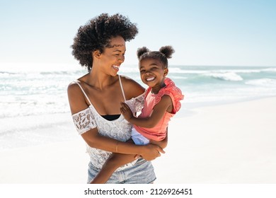 Lächelnde Mutter und schönes Mädchen, die sich während der Sommerferien am Strand amüsieren. Porträt einer glücklichen afrikanisch-amerikanischen Frau, die ein süßes kleines Mädchen hält, während sie mit Kopierraum in die Kamera schaut.