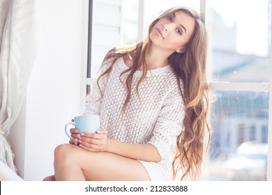 朝のコーヒーを楽しむ若い女性。20 代の幸せな白人モデルの笑みを浮かべてください。