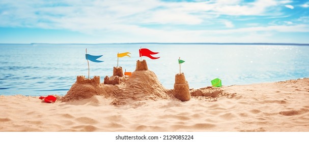 Sand castle with colourful flags on the beach of the sea. Panoramic view. Concept of the vacation and tourism.