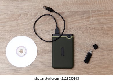 Custodios digitales de la información. Disco duro externo, cd y unidad flash usb en una mesa de madera
