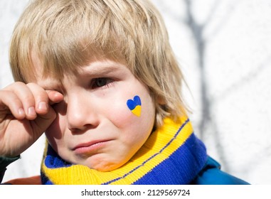 gezicht van een bange jongen, een geschilderd hart op de wang in geelblauwe kleuren van de Oekraïense vlag. Rusland's invasie van Oekraïne, een verzoek om hulp aan de wereldgemeenschap. Kinderen vragen om vrede