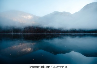 Wintermorgennebel über dem Königssee in Berchtesgaden. Reflexion über die Wasseroberfläche der felsigen bayerischen Alpen. Dunkle geheimnisvolle Atmosphäre.