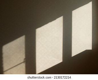 Sunlight from window falls on light wall with ornament. Sun flares is polygonal in shape. Abstract background with light and shaded areas. Diamonds, stripes. Light gradient. Copy space.
