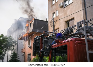 消防車の青いライトとサイレンのクローズ アップ写真。背景に建物が燃えています。