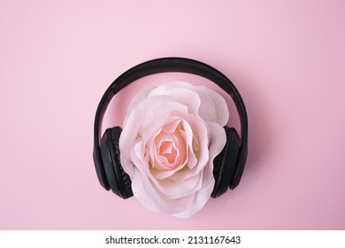Big flower with headphones on pastel pink background.