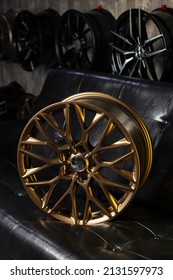 車のリムのショールームで黒革のソファにスタイリッシュな新しい光沢のあるゴールドの車のリム
