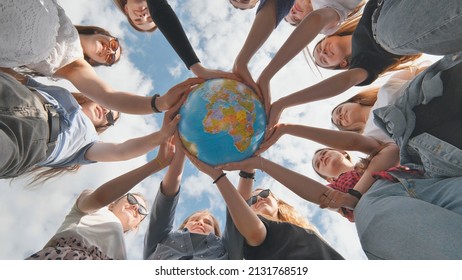 Concetto di conservazione della Terra. 11 ragazze abbracciano il globo terrestre con le loro mani.