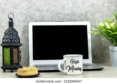 laptop mit leerem bildschirm für ihr logo oder sie arbeiten mit lilienblumentopf und hallo montag auf tasse kaffee und mandelkuchen auf holztisch