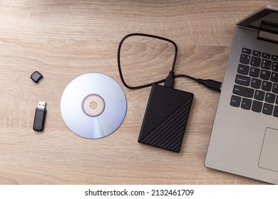 Custodios digitales de la información. Disco duro externo, cd y unidad flash usb, computadora portátil en una mesa de madera