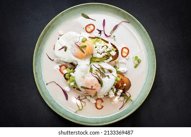 Telur Benediktus untuk sarapan sehat, alpukat di atas roti panggang dengan sayuran di atas piring putih, tampak atas