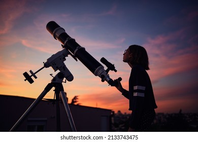 Cô gái với kính viễn vọng thiên văn đang ngắm sao dưới bầu trời chạng vạng.