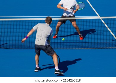 Jugadores de tenis jugando al tenis en una cancha dura en un día soleado