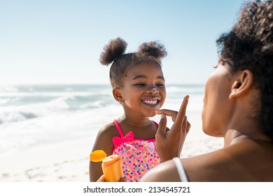 Madre joven que aplica protector solar en la nariz de su hija en la playa con espacio para copiar. Mano de mujer negra poniendo loción solar en la cara de una niña. Linda niña afroamericana con crema bloqueadora solar.