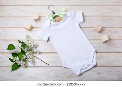 White cotton baby short sleeve onesie mockup with white lilac and children toy blocks. Design gender neutral bodysuit template, newborn romper print presentation mock up