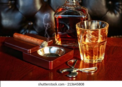 Un vaso de whisky y puro en una mesa de madera