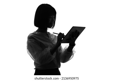 Siluet wanita Asia menggunakan PC tablet.
