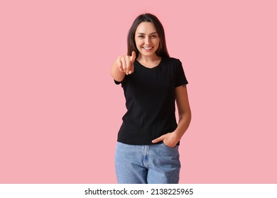色の背景上のビューアーで指している空白の t シャツの若い女性