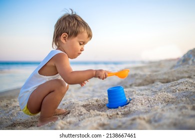 陽気で熱狂的な少年が海の砂浜でおもちゃで遊び、ビーズやタレットを作り、明るく晴れた夏休みに舞台裏で誰かに微笑んでいる