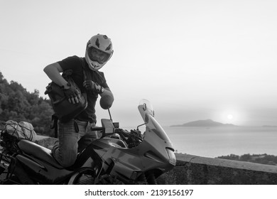 Motorcyklist mand nyder smuk solnedgang, hav og bjerge. Turisme og eventyr. Motorcykel tur rejse. copyspace til din individuelle tekst. Sort og hvid