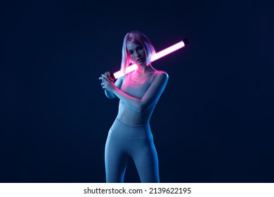 Woman in futuristic costume. Female in modern VR glasses interacting with network while having virtual reality experience. Augmented reality game, future technology, AI concept. VR. Neon blue light.