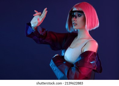 Woman in futuristic costume. Female in modern VR glasses interacting with network while having virtual reality experience. Augmented reality game, future technology, AI concept. VR. Neon violet light.