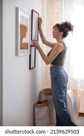 現代の女性の壁掛け写真は、木製のフレームに飾られたスカンジのミニマルなスタイルの部屋のアパートです。ブルネットの巻き毛の女性がエレガントな装飾要素を付けて居心地の良い家の白い光のインテリア
