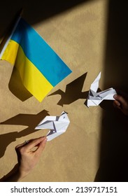 2 papieren vredesduifjes en Oekraïense vlag. Blijf bij Oekraïne. Stop de oorlog in Oekraïne. Roep de wereldgemeenschap om hulp. spelletjes van schaduw en licht