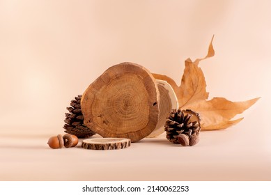 ベージュの背景に木製の表彰台、装飾、紅葉のセット。秋の季節の背景